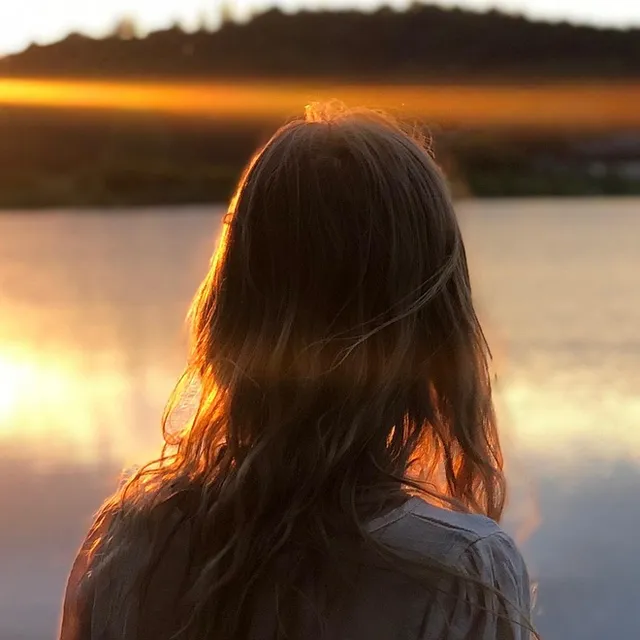 Example of a Facebook profile picture cropped to a circle: the back of a woman's head against a sunset over a lake